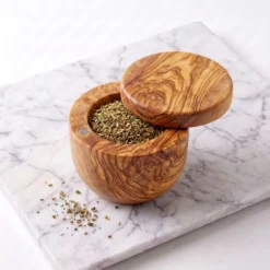 Boîte pivotante en bois d’olivier ouverte et remplie d’herbes séchées