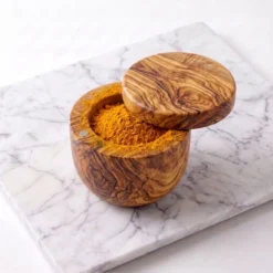 Boîte pivotante en bois d’olivier ouverte et remplie de curcuma moulu