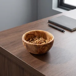 Round olive wood bowl with walnuts on a desk