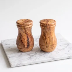 Duo salière et poivrière en bois d’olivier en vue studio sur marbre clair