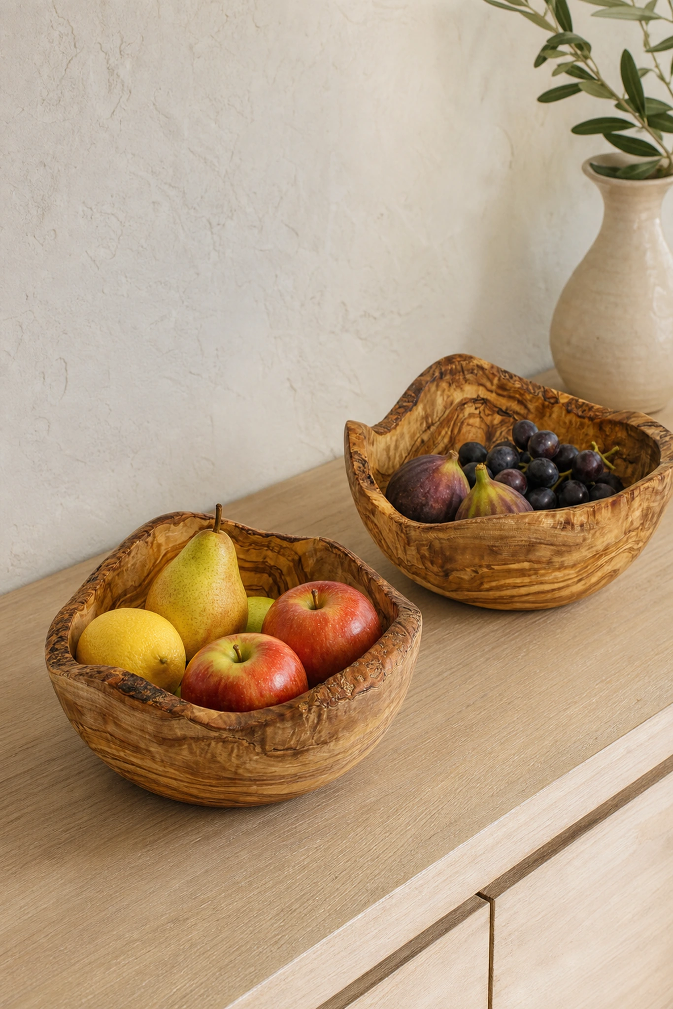 Deux saladiers rustiques en bois d’olivier remplis de fruits sur un meuble clair