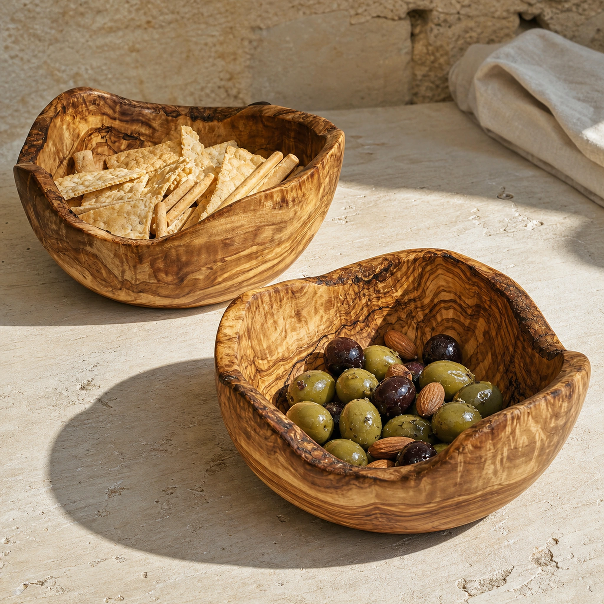 Deux saladiers rustiques de 20 cm contenant des olives, des amandes, des crackers et des gressins