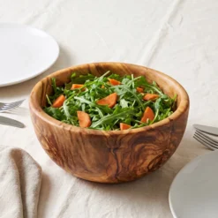 Saladier en bois d’olivier de 28 cm rempli d’une salade de roquette et de carottes sur une table