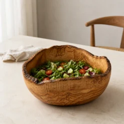 Très grand saladier rustique en bois d’olivier rempli d’une salade sur une table claire