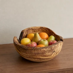 Saladier rustique en bois d’olivier rempli de fruits sur un meuble en bois