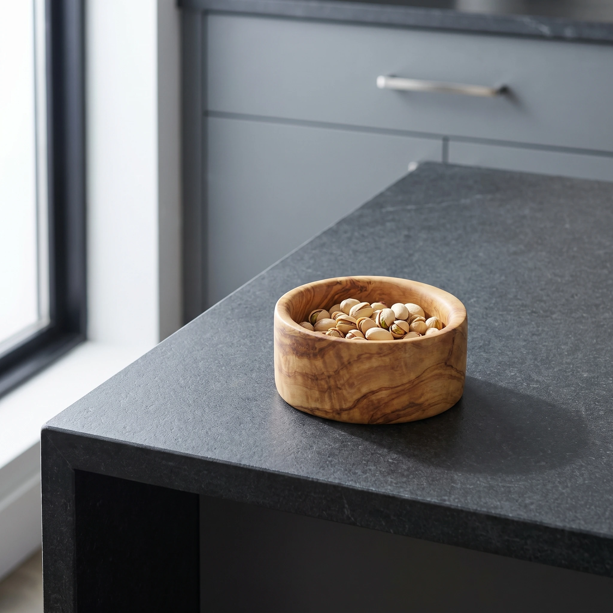 Olive wood snack bowl with pistachios on a kitchen island
