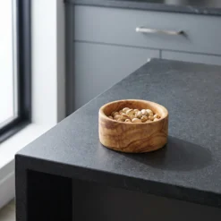 Petit bol apéritif en bois d’olivier avec pistaches sur un îlot de cuisine