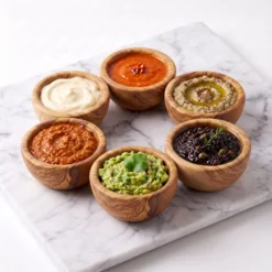 Six petits bols en bois d’olivier garnis de sauces