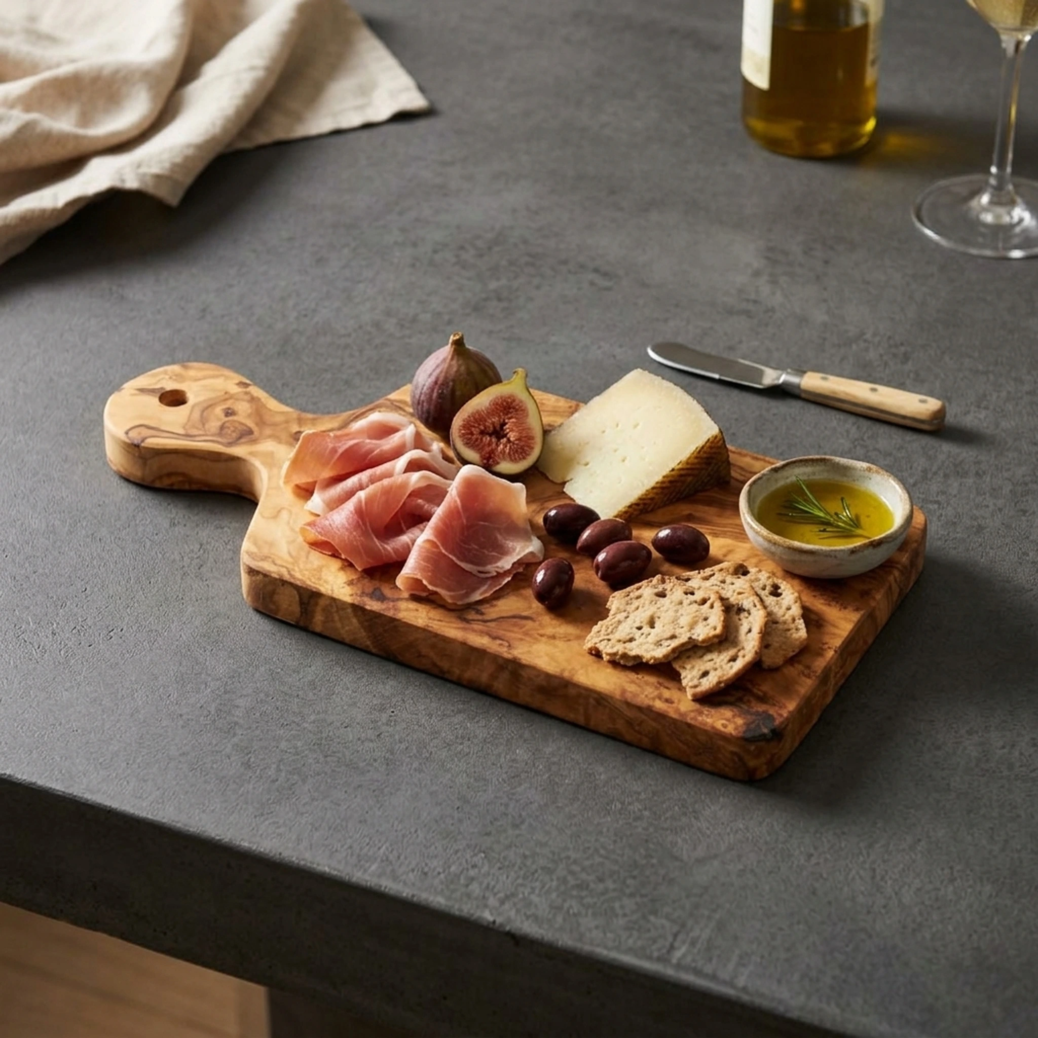 Planche en bois d’olivier garnie de charcuterie, fromage et figues sur un plan de travail sombre