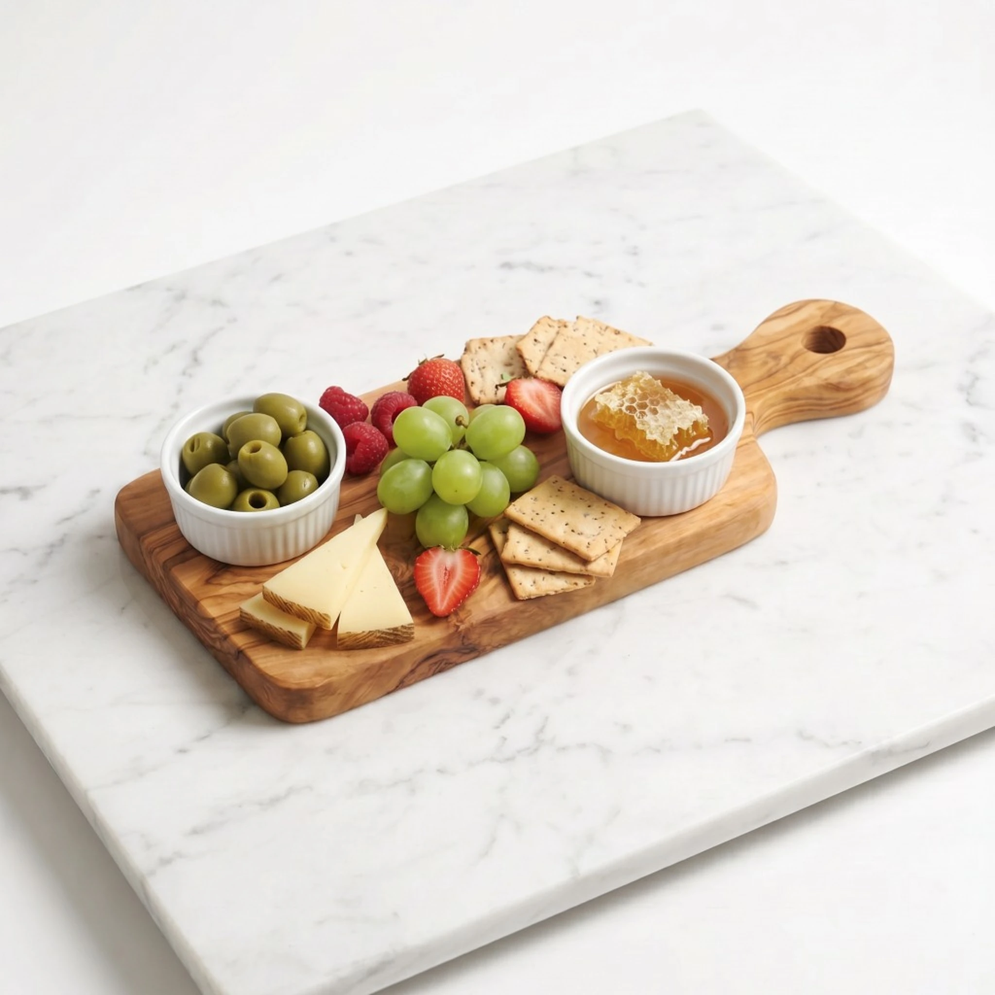 Planche en bois d’olivier garnie d’olives, de fruits et de fromage sur marbre blanc