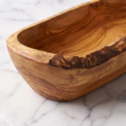 Gros plan sur le veinage et le bord naturel d’une coupe en bois d’olivier