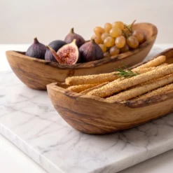 Two olive wood baskets serving fruit, bread and grissini