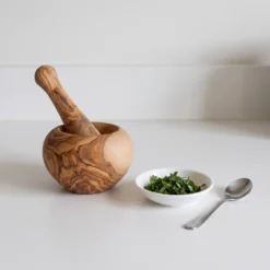 Mortier et pilon en bois d’olivier avec herbes fraîches sur un plan de travail