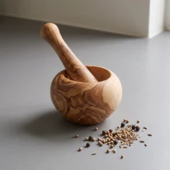 Olive wood mortar and pestle with spices on a grey kitchen worktop