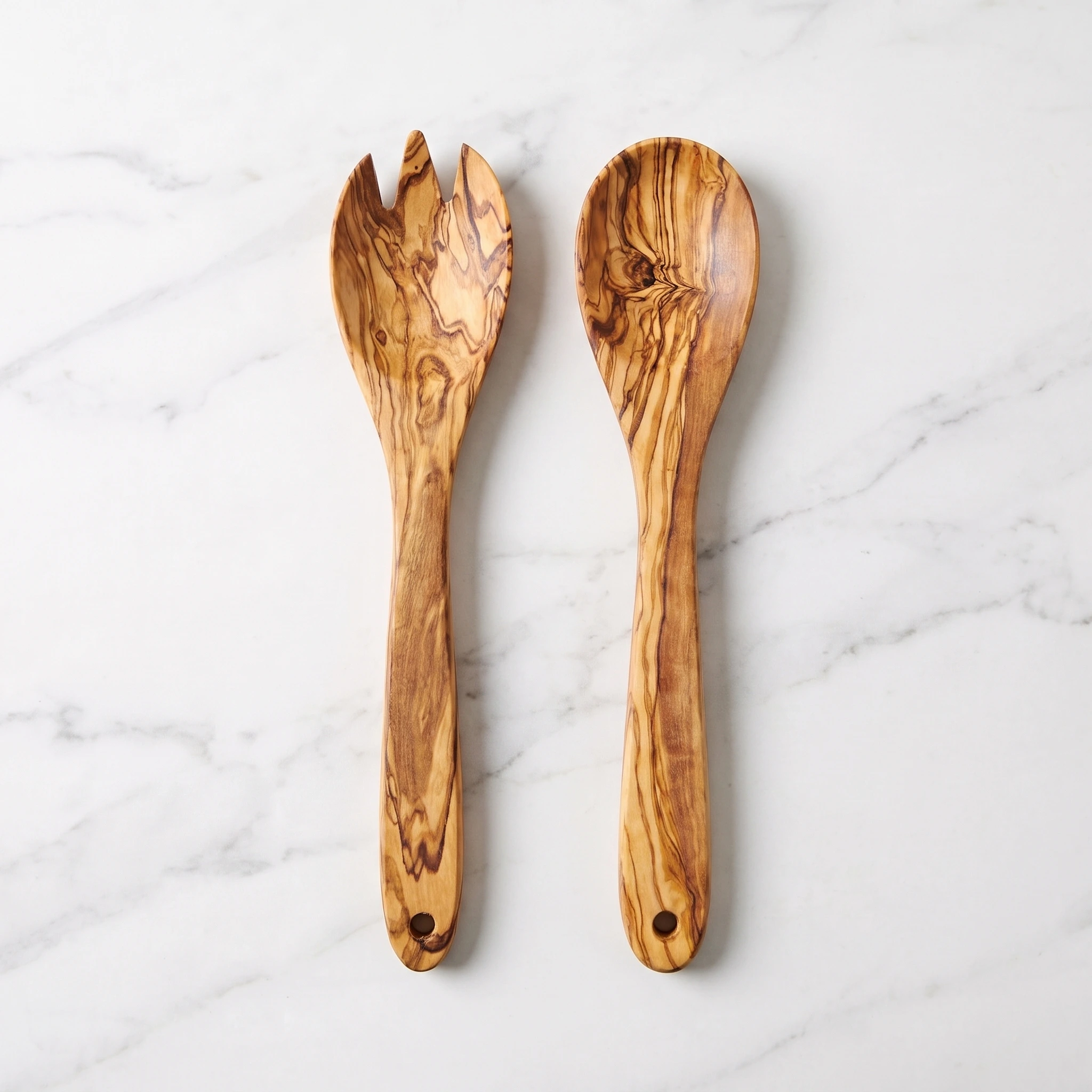 Olive wood salad servers aligned, viewed from above on white marble