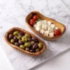 Deux raviers à tapas en bois d’olivier garnis d’olives et de feta sur marbre clair