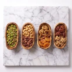 Four olive wood tapas bowls filled with assorted nuts and dried fruit