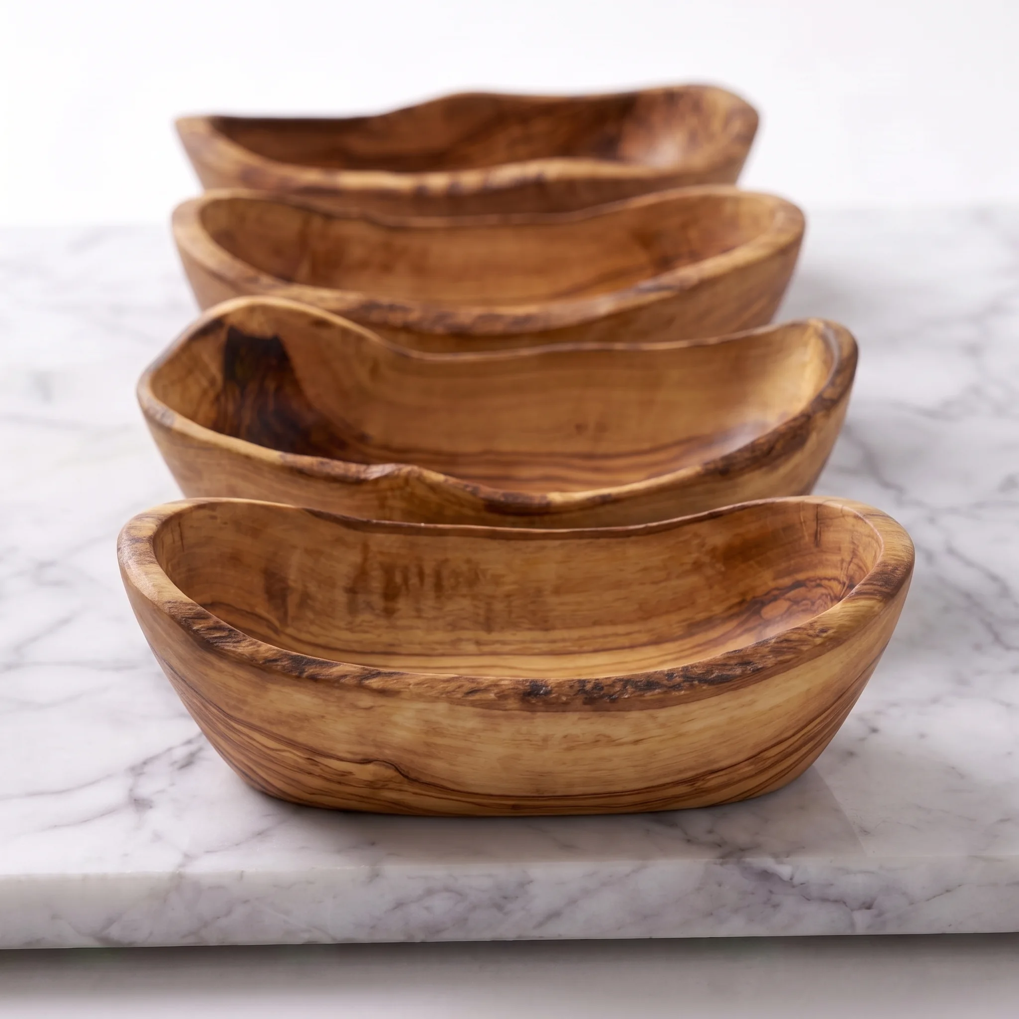 Close view of the natural contours of four olive wood tapas bowls