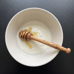 Cuillère à miel en bois d’olivier avec un bol de yaourt et du miel