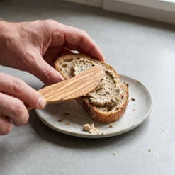 Olive wood butter spreader spreading cream on bread