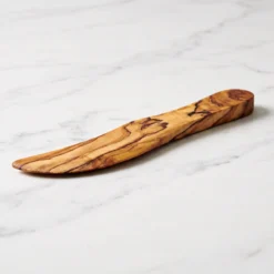 Profile of an olive wood butter spreader on white marble
