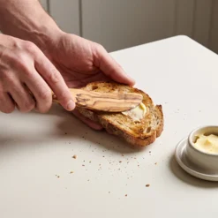 Tartineur en bois d’olivier étalant du beurre sur du pain grillé
