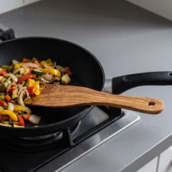 Olive wood spatula in a frying pan with vegetables