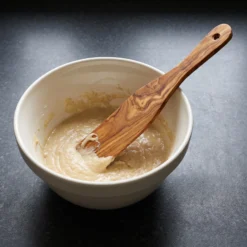 Spatule en bois d’olivier posée dans un bol de pâte