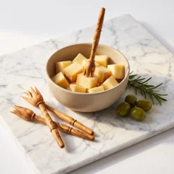 Quatre pics en bois d’olivier présentés avec des bouchées de fromage pour illustrer leur usage