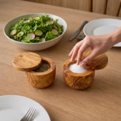 Hand taking salt from the olive wood cellar set presented at the table