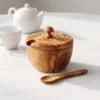 Closed olive wood sugar bowl beside a cup and teapot