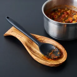 Cuillère de cuisson posée sur un porte-cuillère en bois d’olivier près d’une casserole