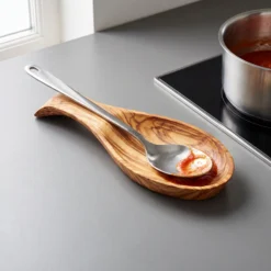 Grande cuillère de cuisine posée sur un porte-cuillère en bois d’olivier