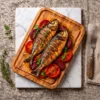 Deux poissons grillés présentés sur une planche rectangulaire en bois d’olivier